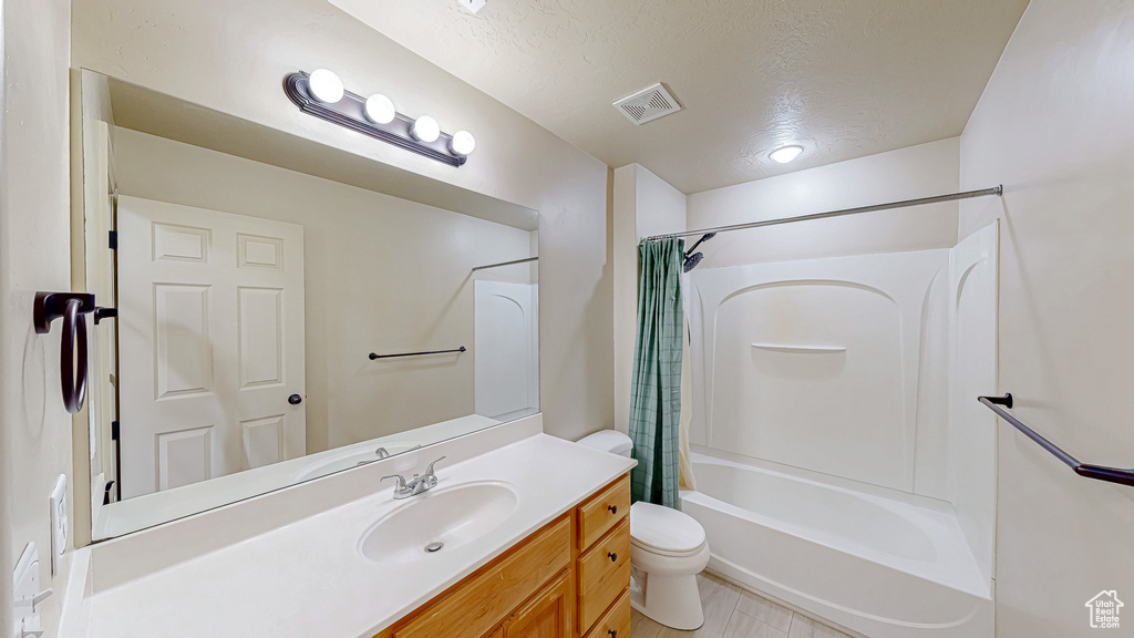 Full bath with toilet, vanity, a textured ceiling, and shower / bath combination with curtain