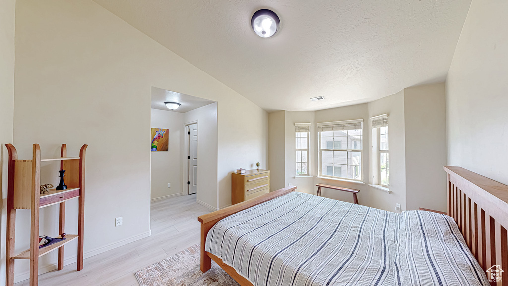 Bedroom featuring light wood-style flooring, baseboards, and a textured ceiling