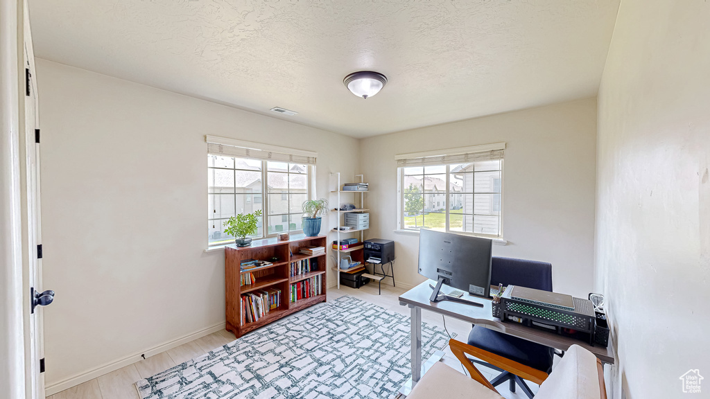 Office featuring baseboards, a textured ceiling, and light wood-style floors