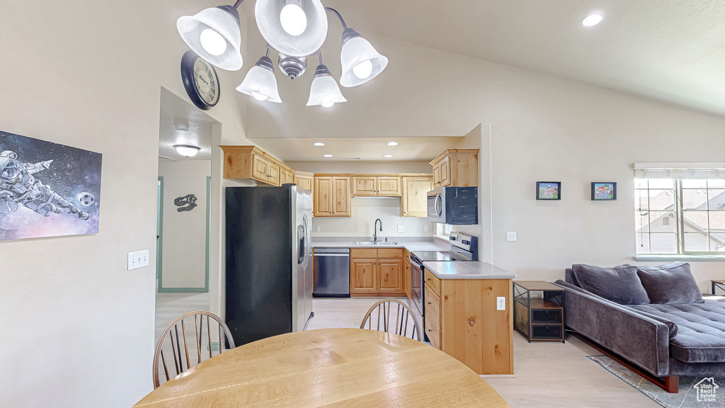 Kitchen with stainless steel appliances, a sink, lofted ceiling, light brown cabinetry, and light countertops