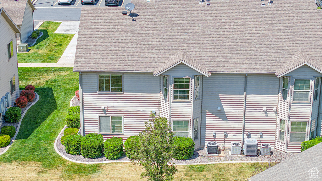 Rear view of house featuring roof with shingles, a yard, and central AC unit
