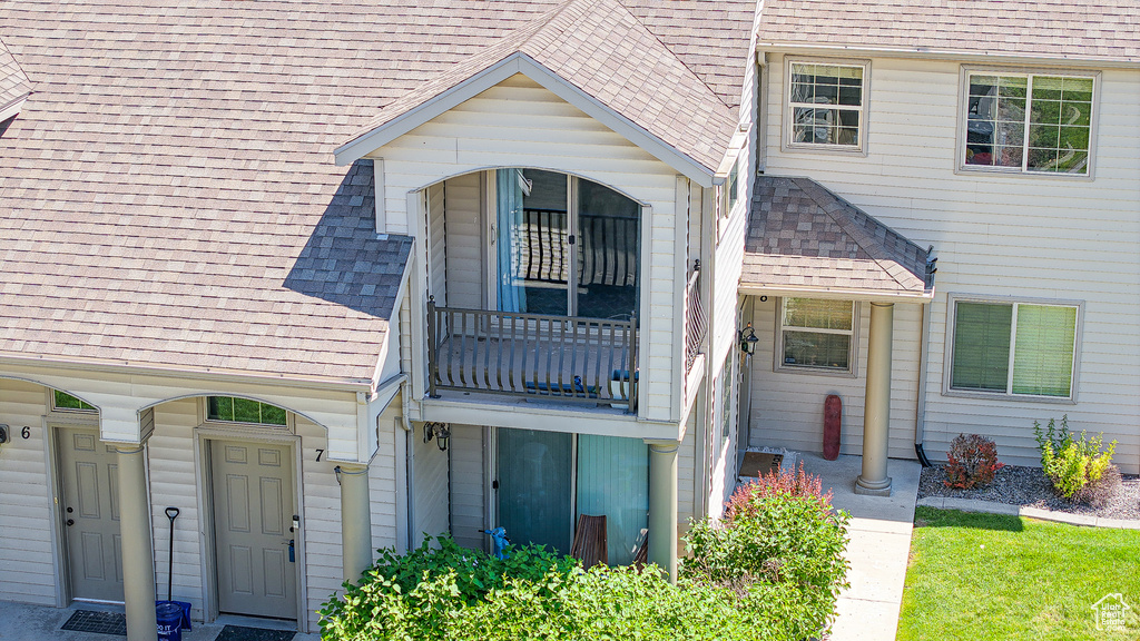 View of exterior entry featuring a shingled roof