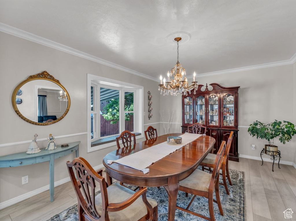 Dining area with a chandelier, crown molding, light wood-style flooring, and baseboards