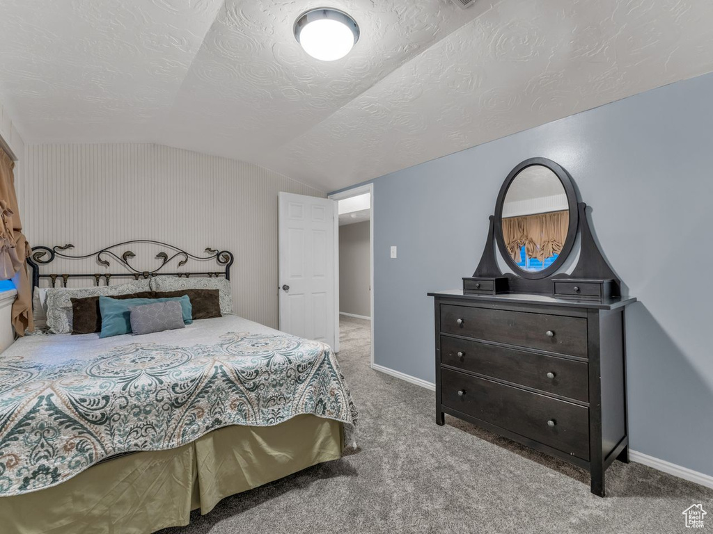 Bedroom featuring lofted ceiling, a textured ceiling, carpet flooring, and baseboards