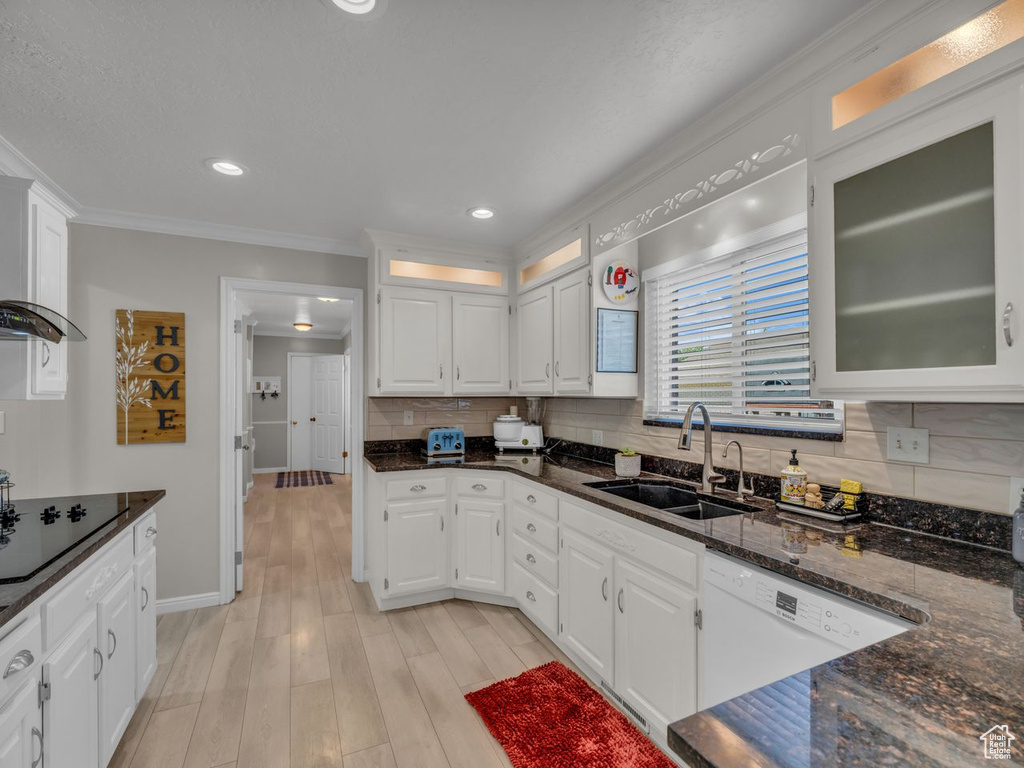 Kitchen featuring a sink, black electric stovetop, ornamental molding, white cabinetry, and decorative backsplash