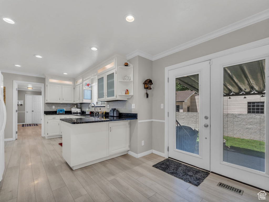 Kitchen featuring a peninsula, a sink, open shelves, white cabinets, and baseboards