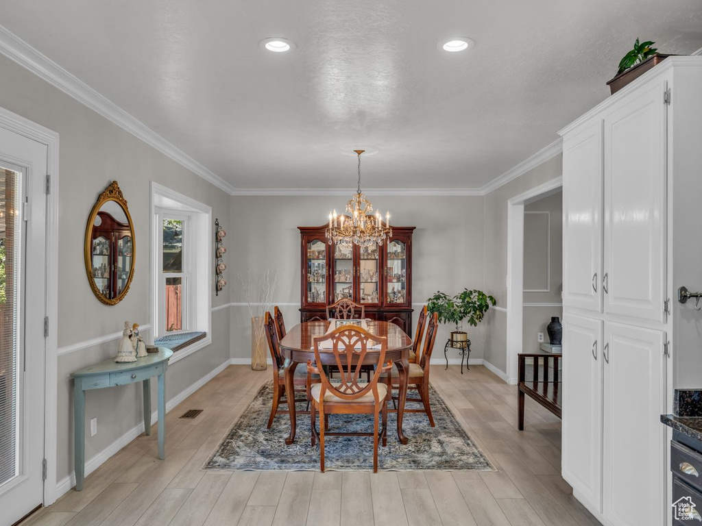 Dining area featuring a chandelier, ornamental molding, light wood finished floors, and baseboards