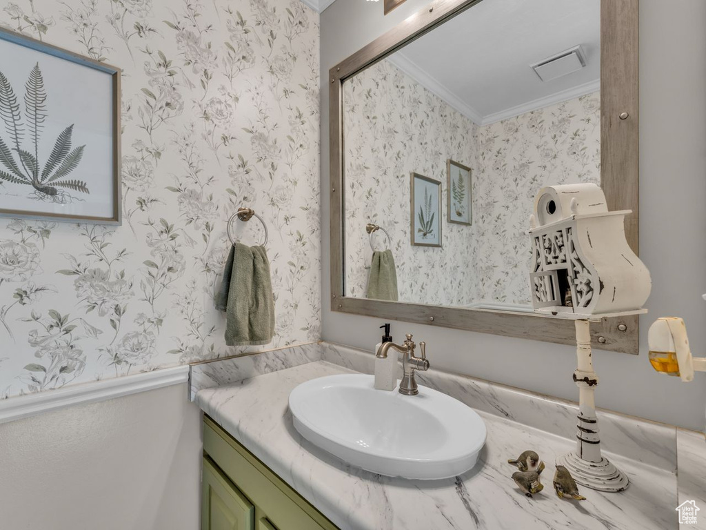 Bathroom featuring wallpapered walls, ornamental molding, and vanity