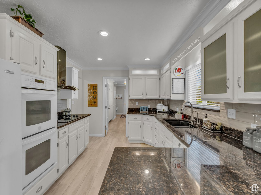 Kitchen with a sink, double oven, crown molding, white cabinets, and decorative backsplash