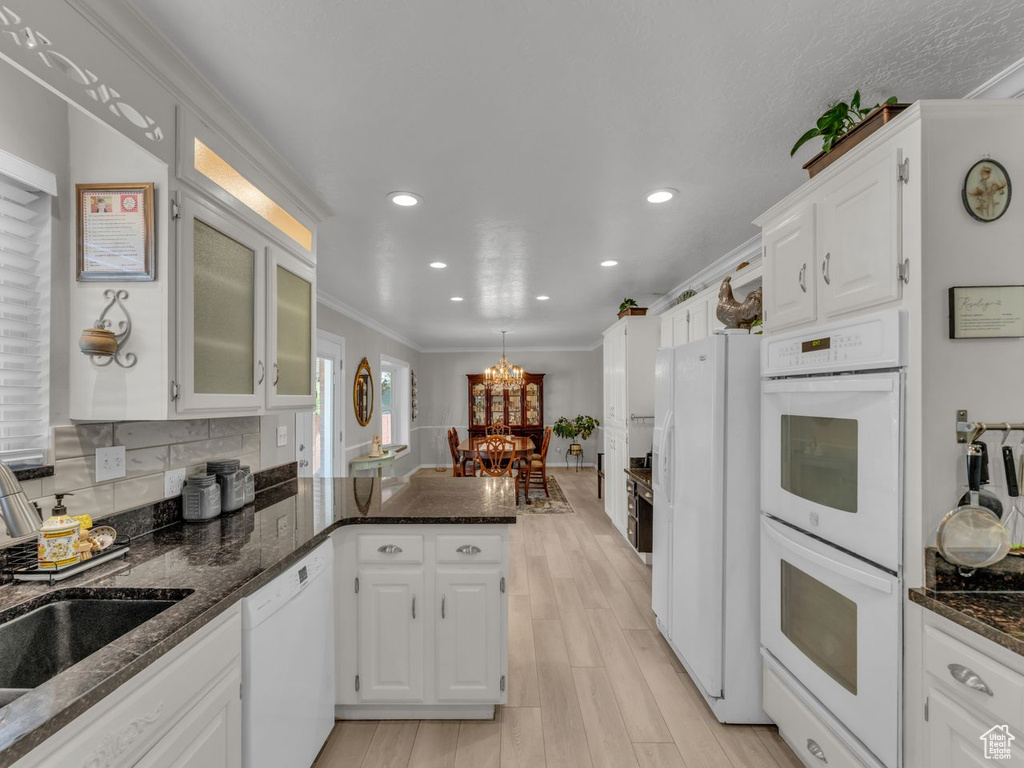Kitchen with white appliances, a peninsula, white cabinetry, a sink, and recessed lighting