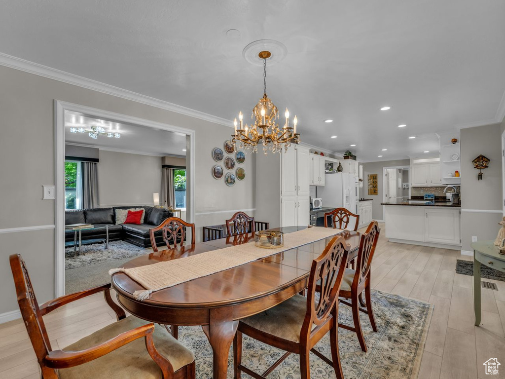 Dining area featuring a chandelier, recessed lighting, crown molding, and light wood-type flooring