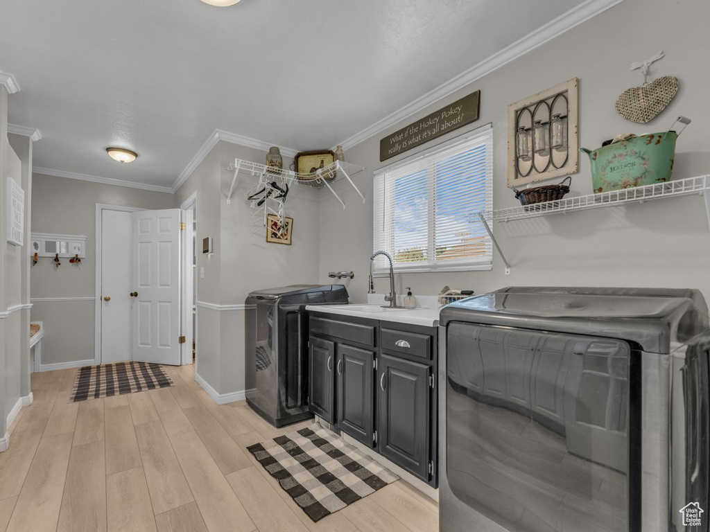 Laundry room featuring cabinet space, washer and clothes dryer, baseboards, light wood-type flooring, and ornamental molding