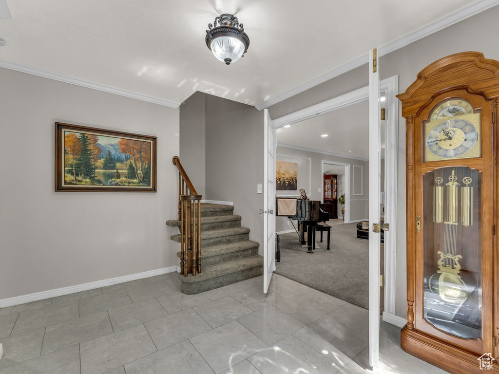 Entryway with ornamental molding, stairs, and baseboards