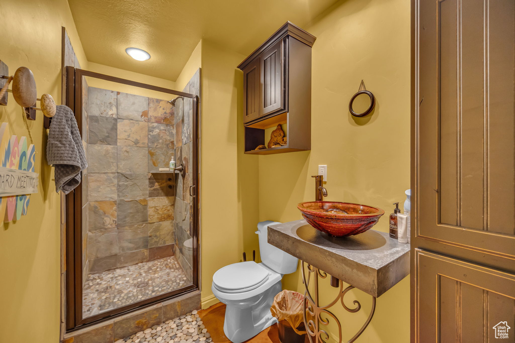 Bathroom featuring a sink, toilet, and a shower stall