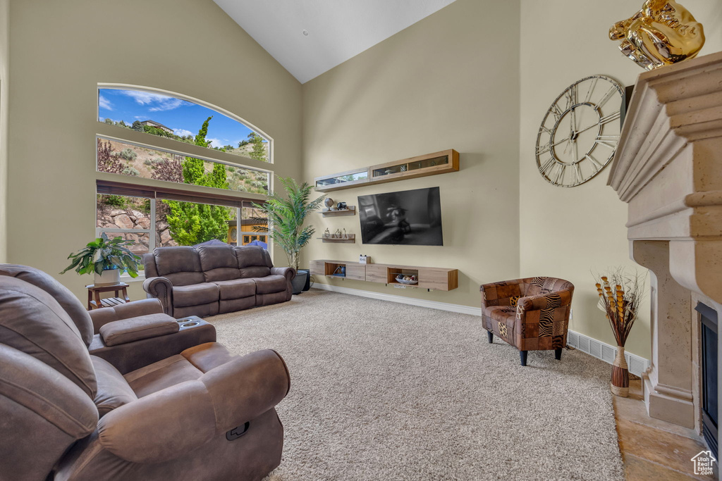 Living room featuring high vaulted ceiling, a high end fireplace, carpet flooring, and baseboards