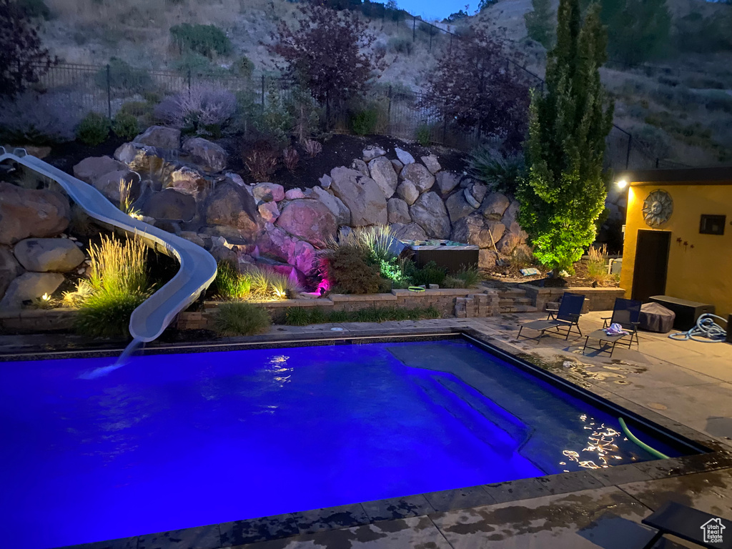 View of pool with a water slide, a patio, and a mountain view