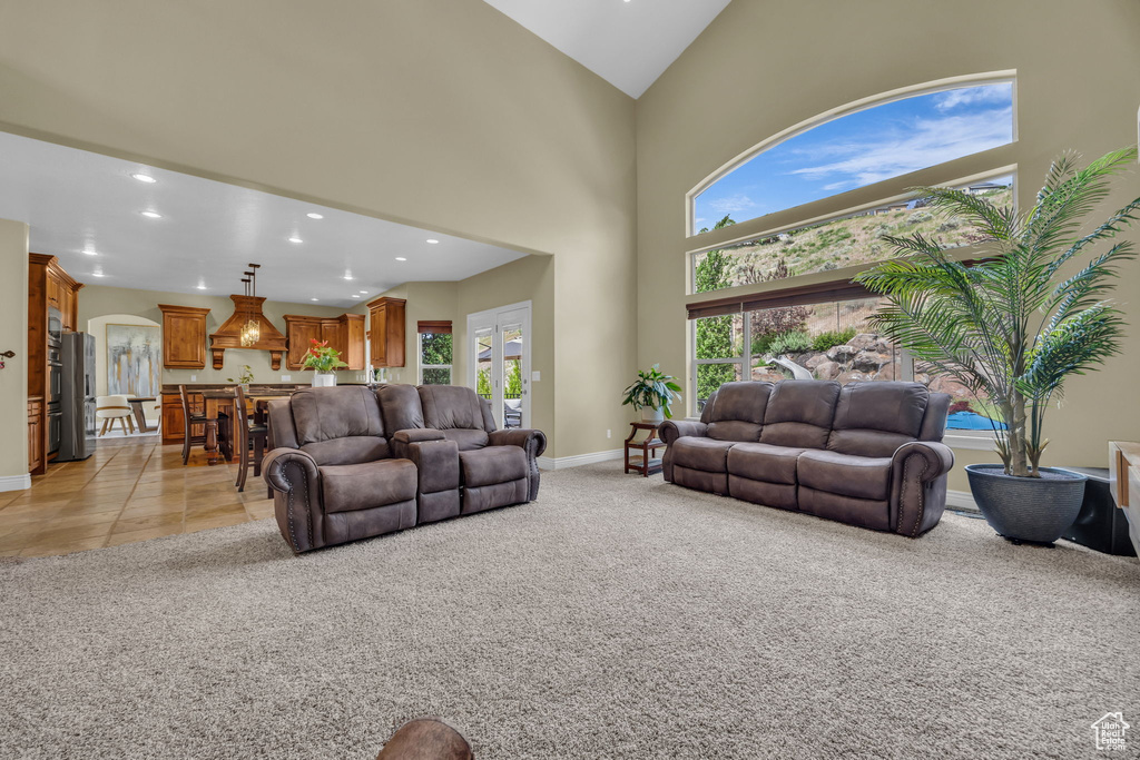 Living room featuring recessed lighting, plenty of natural light, arched walkways, baseboards, and light colored carpet