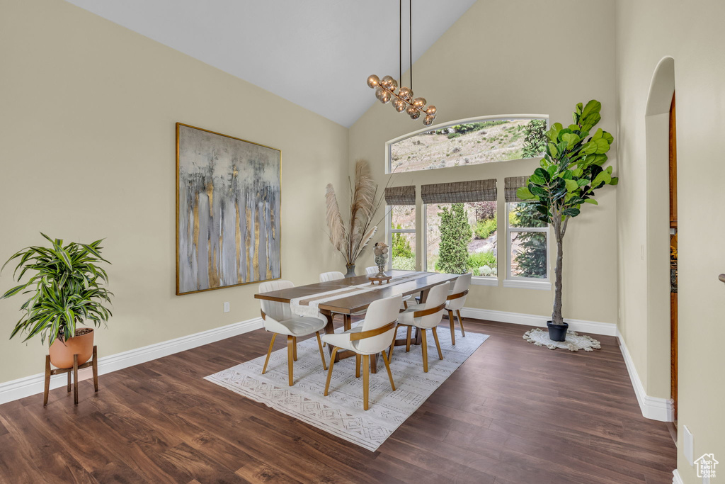 Dining room with wood finished floors, baseboards, arched walkways, and high vaulted ceiling