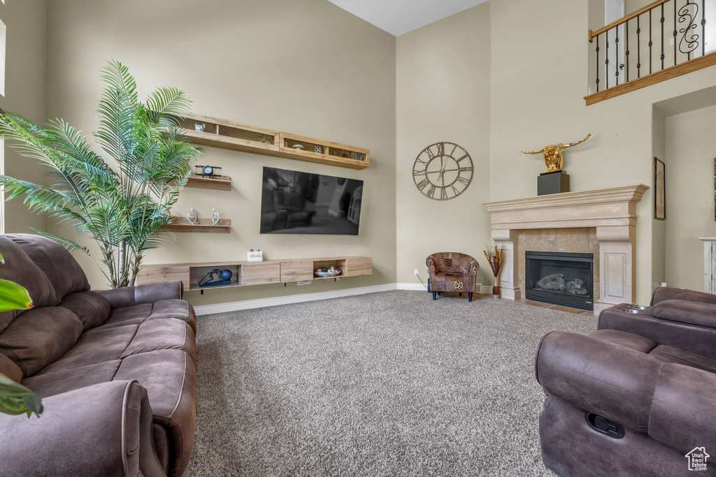 Living area with carpet flooring, a high ceiling, baseboards, and a fireplace