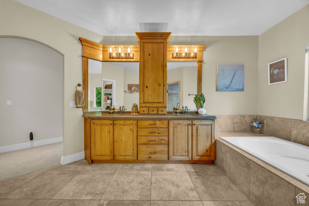 Bathroom with double vanity, a garden tub, and baseboards