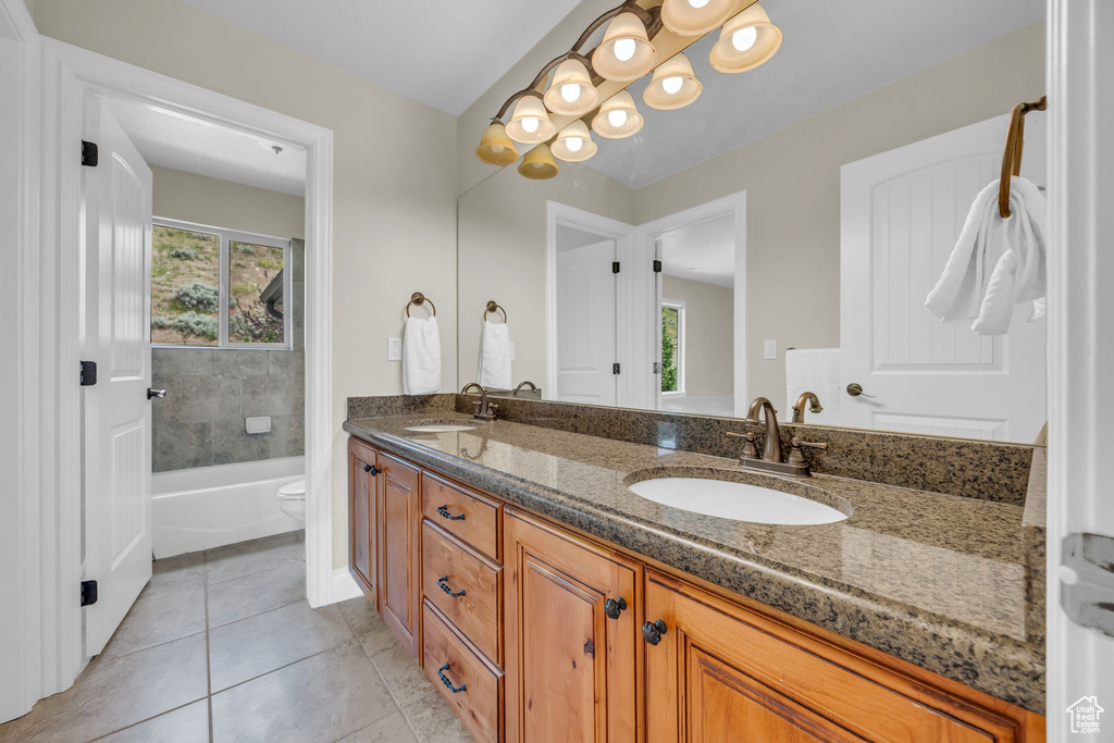 Full bath featuring double vanity, toilet, and tile patterned flooring