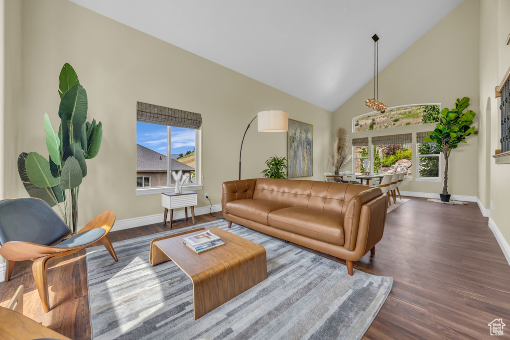 Living room featuring baseboards, high vaulted ceiling, and dark wood-style floors