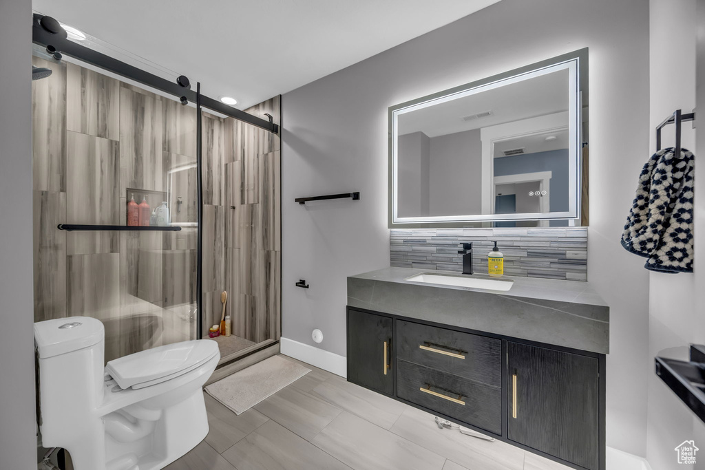 Bathroom with toilet, tasteful backsplash, vanity, and a shower stall