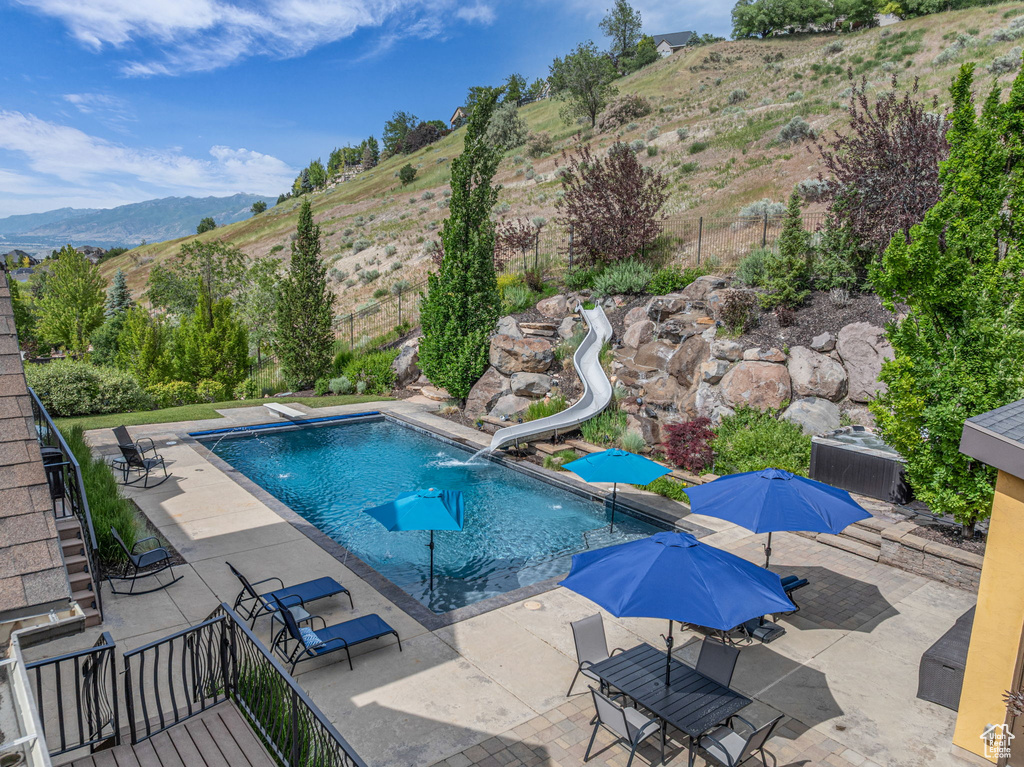View of pool featuring a patio, a mountain view, and a water slide