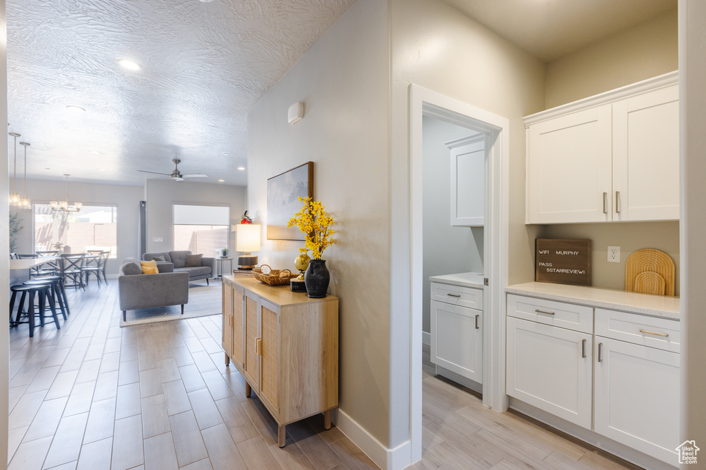 Corridor with light wood finished floors, a chandelier, recessed lighting, and baseboards