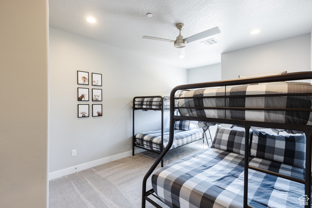 Bedroom featuring light colored carpet, baseboards, and a ceiling fan