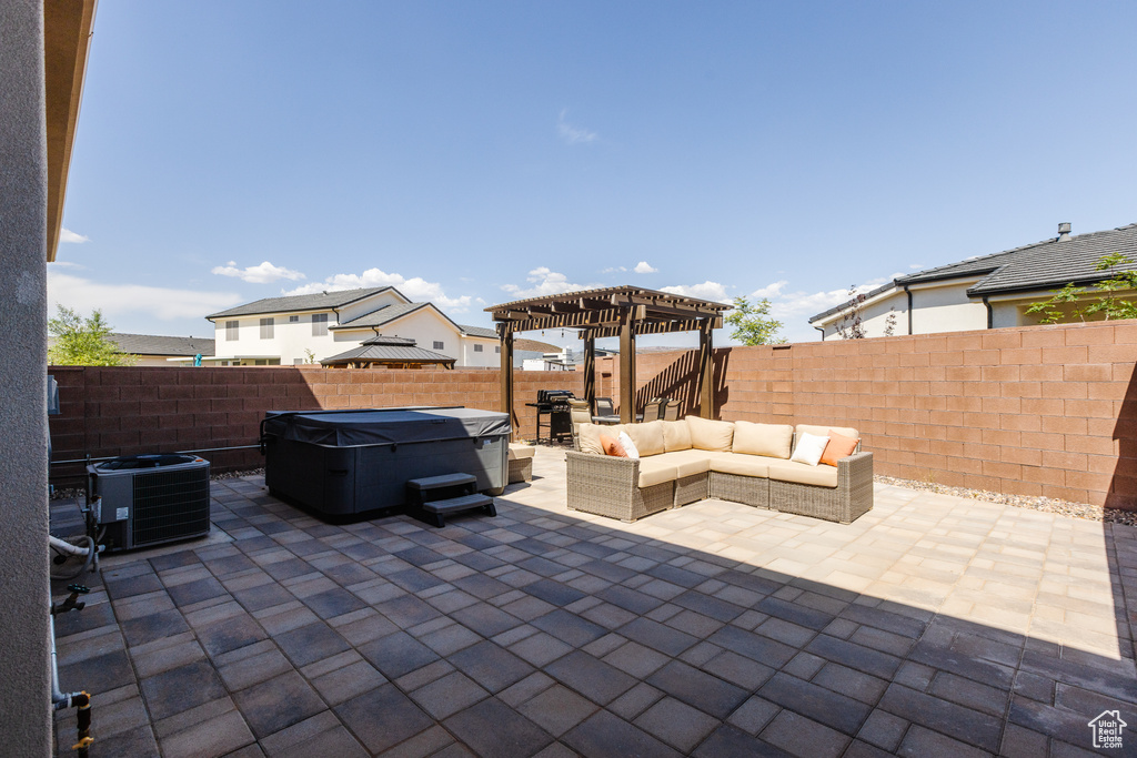 Fenced backyard featuring central AC unit, a pergola, a patio area, outdoor lounge area, and a hot tub