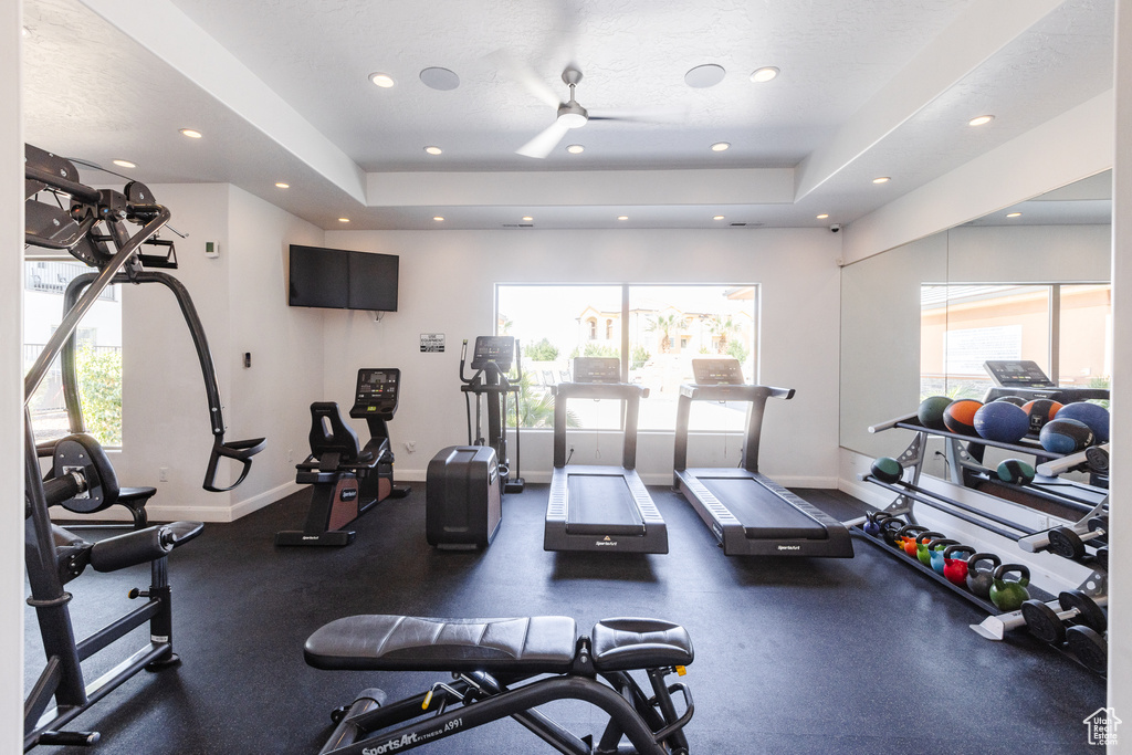 Exercise room featuring baseboards, recessed lighting, ceiling fan, and a tray ceiling