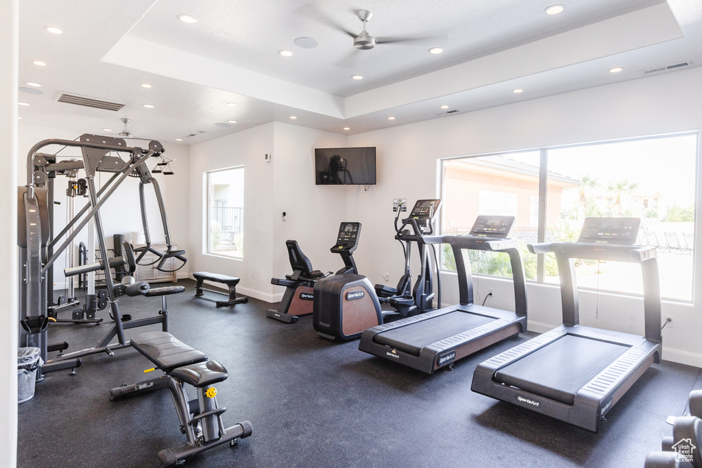 Gym with recessed lighting, baseboards, ceiling fan, and a raised ceiling
