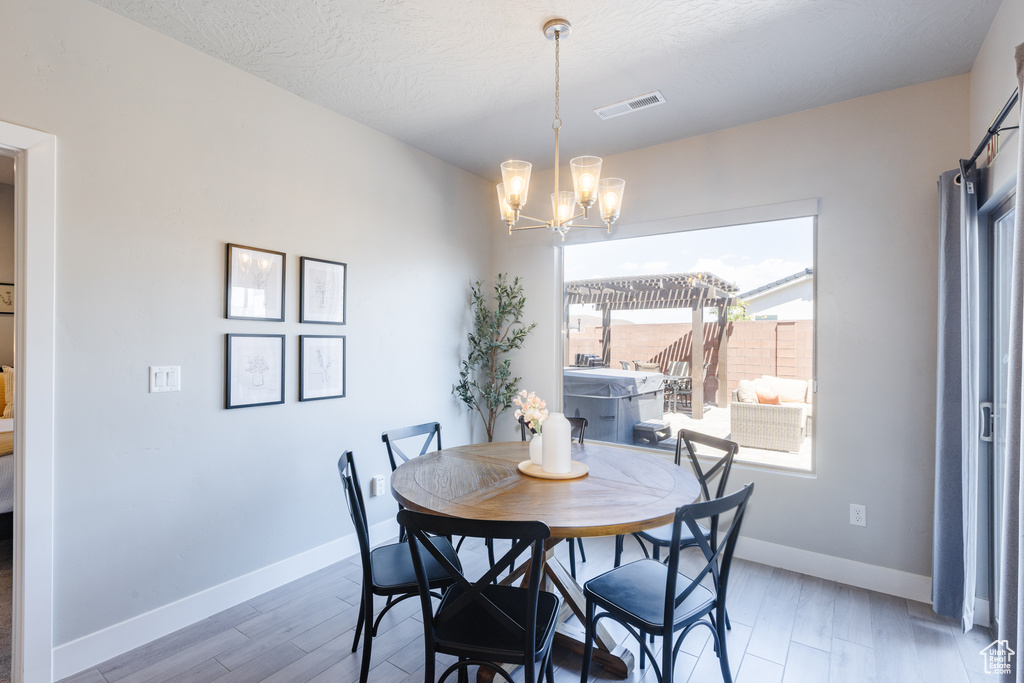 Dining area with a chandelier, baseboards, and light wood-style floors