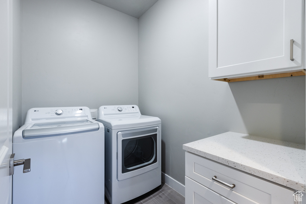 Washroom featuring washer and dryer, cabinet space, and baseboards