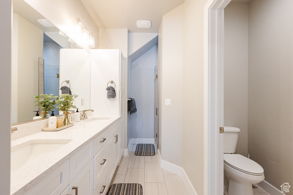 Bathroom with double vanity, toilet, and baseboards