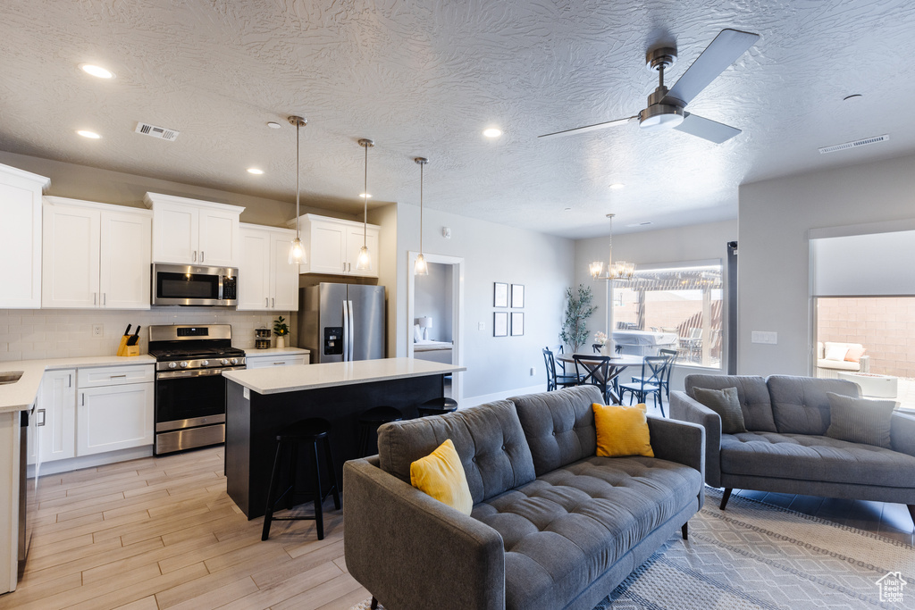 Kitchen with stainless steel appliances, open floor plan, light countertops, tasteful backsplash, and a textured ceiling