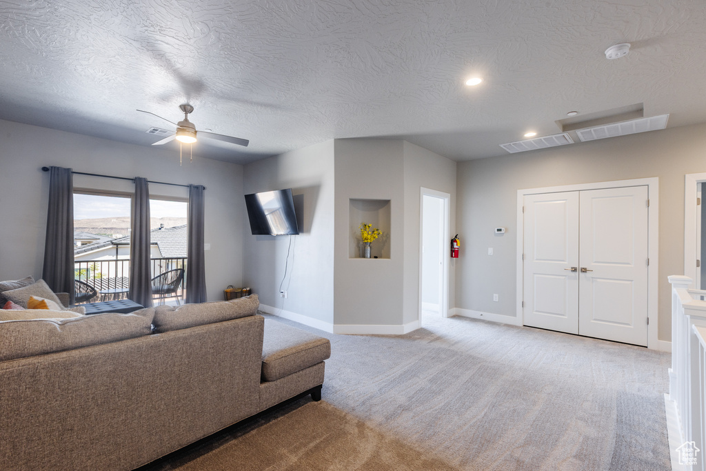 Living room featuring light carpet, ceiling fan, baseboards, recessed lighting, and a textured ceiling