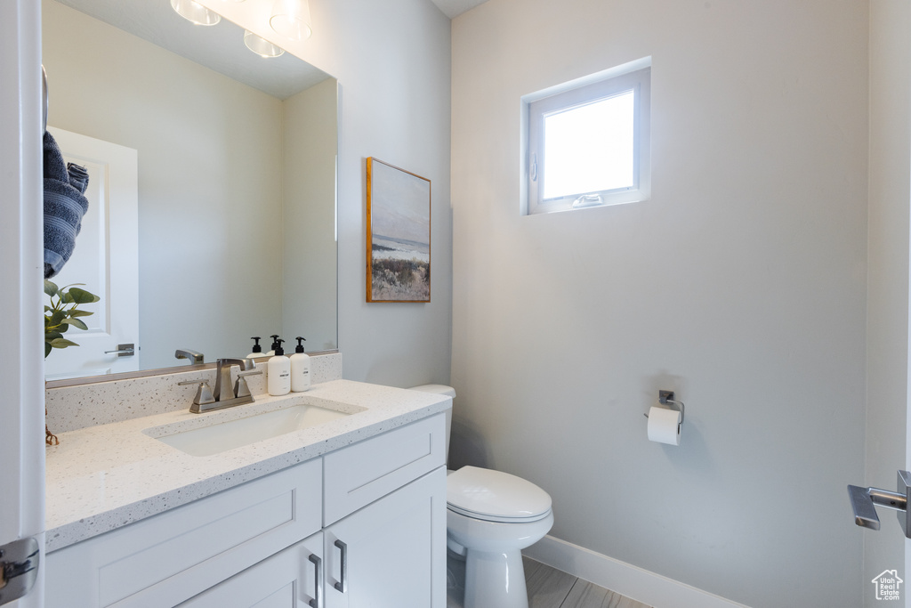 Half bathroom with toilet, vanity, and baseboards