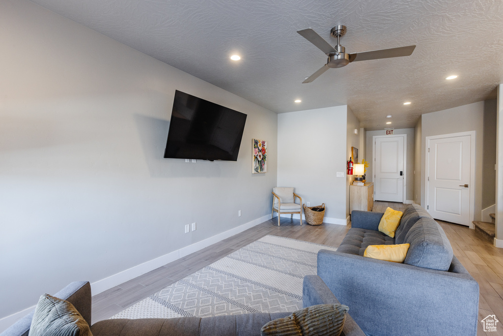 Living area featuring a ceiling fan, light wood-style flooring, baseboards, recessed lighting, and a textured ceiling