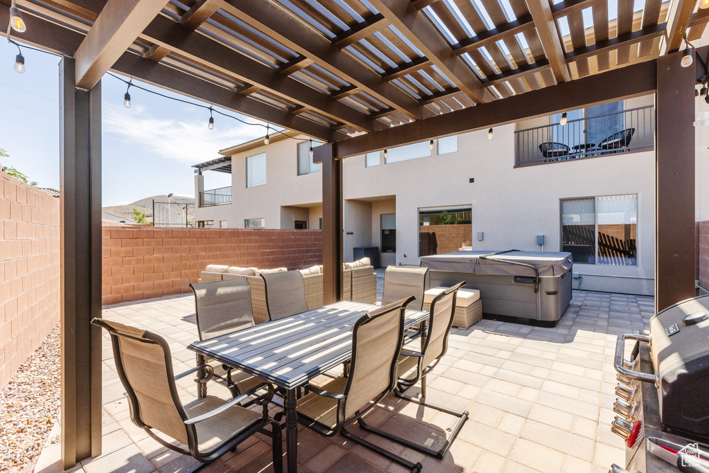 Fenced backyard with a hot tub, a patio, outdoor dining space, and a pergola