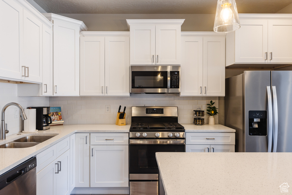 Kitchen with appliances with stainless steel finishes, a sink, white cabinetry, and decorative backsplash