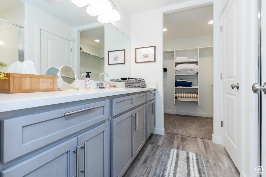 Full bathroom featuring vanity, a spacious closet, wood finished floors, recessed lighting, and baseboards