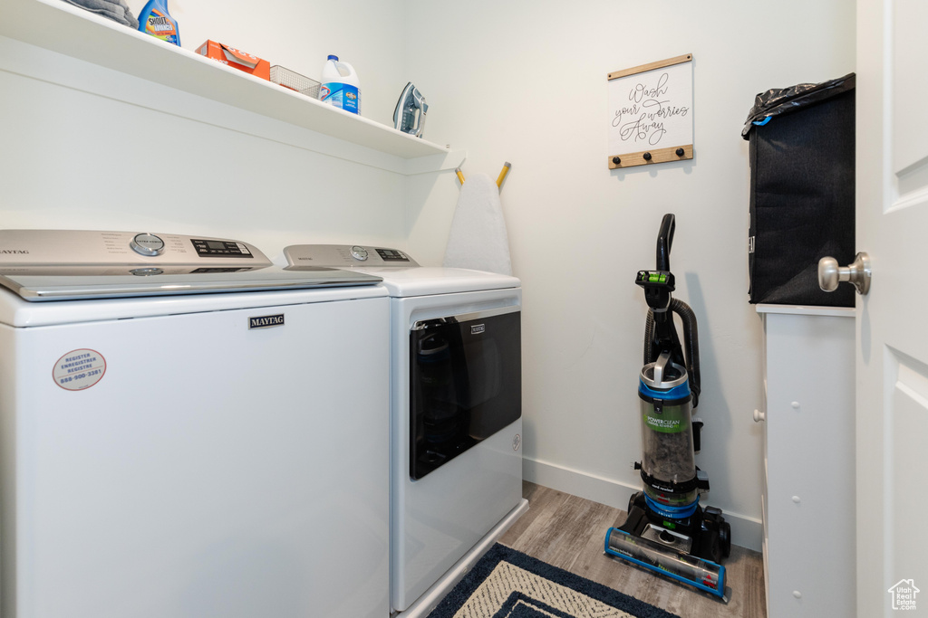 Washroom with independent washer and dryer, light wood-style floors, and baseboards