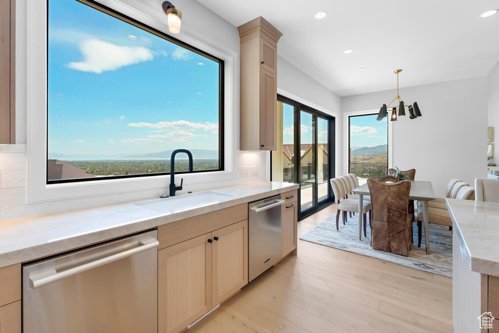 Kitchen with stainless steel dishwasher, a sink, recessed lighting, light wood-style floors, and pendant lighting