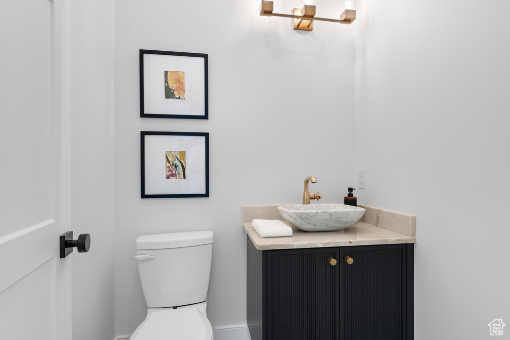 Half bath with toilet, vanity, and baseboards