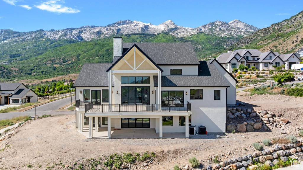 Rear view of house featuring a balcony, stucco siding, a chimney, and a mountain view