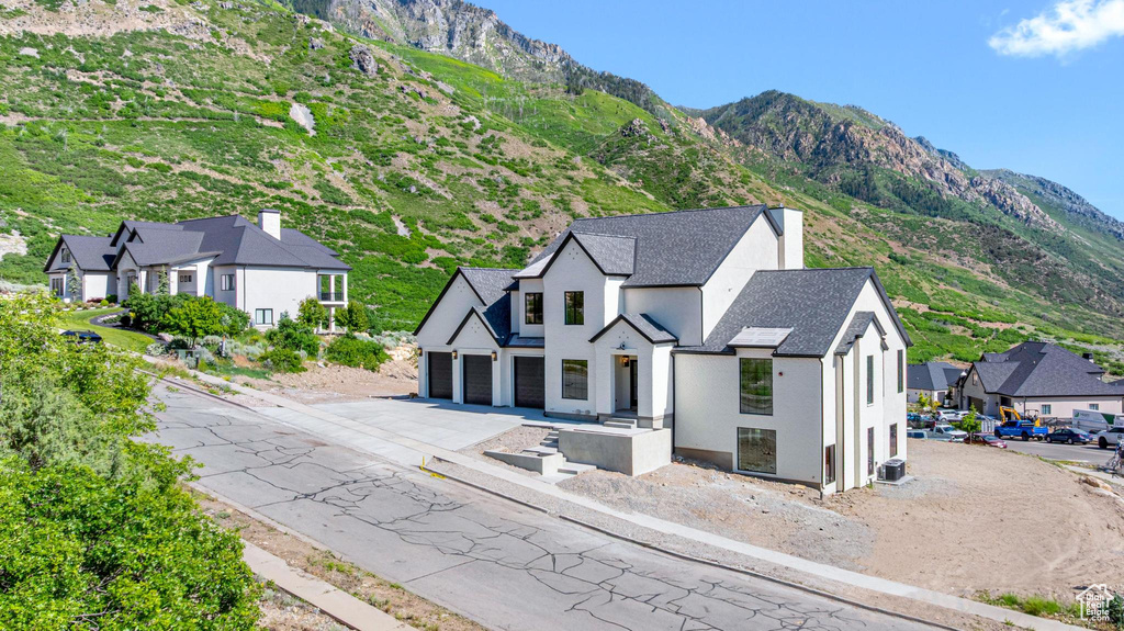 View of front facade with asphalt driveway, stucco siding, a garage, and a mountain view