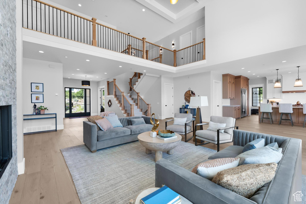 Living room with a towering ceiling, healthy amount of natural light, light wood-type flooring, stairs, and recessed lighting