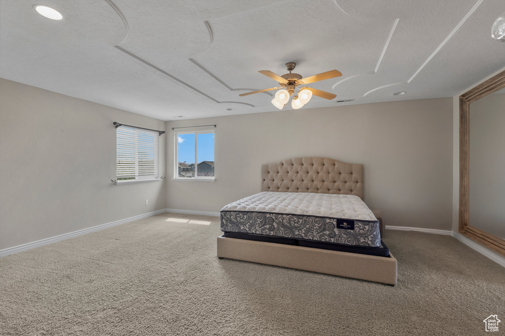 Carpeted bedroom with a textured ceiling, baseboards, and ceiling fan